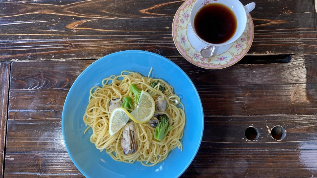 Coffee and pasta on a wooden table. The pasta features lemon and oysters.